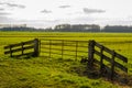 Rusty metal gate between wooden beams enclosed with a chain and