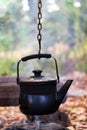 rusty metal kettle on burning firewood pile with blur background in camp Royalty Free Stock Photo