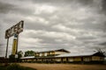 Rusty metal motel sign with wooden old motels under the cloudy and rainy  sky Royalty Free Stock Photo