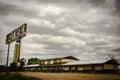 Rusty metal motel sign with wooden old motels under the cloudy and rainy sky