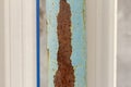 A rusty metal pole with blue paint falling off