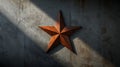 Rusty metal star on concrete wall with light and shadow patterns cast Royalty Free Stock Photo