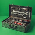 Rusty metal toolbox containing various tools against a green background. Inside, Royalty Free Stock Photo