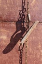 On the rusty metal wall of the village shed hang on the chains used old vintage agricultural tool Royalty Free Stock Photo