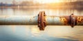 Rusty metallic pipe flange joint against a tranquil water background at sunset. Generative AI Royalty Free Stock Photo