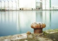 Rusty mooring bollard cast iron at pier shore.A bollard port by a harbour. Sky and water background copyspace. Securing