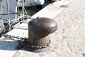 Rusty mooring bollard with an iron chain on the harbor pier Italy, Europe Royalty Free Stock Photo