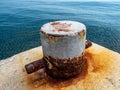 A rusty mooring bolard in two colours