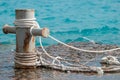 Rusty mooring bollard with ship ropes and clear turquouse sea ocen water on background Royalty Free Stock Photo