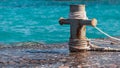 Rusty mooring bollard with ship ropes and clear turquouse sea ocen water on background Royalty Free Stock Photo