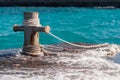 Rusty mooring bollard with ship ropes and clear turquouse sea ocen water on background Royalty Free Stock Photo