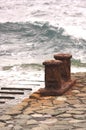 Rusty Noray with ocean waves in the background in a small harbor