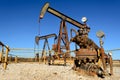 Rusty Oilfield Pumpjack rocking horse over a wellhead. Clear b