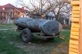 Rusty old big barrel on wheels. Broken tank for liquids, standing on backyard in the village.