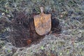 Rusty old broken shovel without handle laying in a freshly dug hole