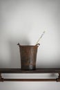 Rusty old bucket on a wooden shelf with a single artist brush Royalty Free Stock Photo