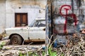 Rusty old car parked next to a brick wall with communism sign (hammer and sickle) on it Royalty Free Stock Photo