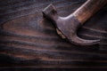 Rusty old-fashioned claw hammer on vintage dark wooden board clo