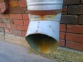 Rusty old metal downspout on blurred red brick wall. Gutter pipe. Water shoot. Downpipe on building facade background. Housing and Royalty Free Stock Photo