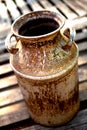 Rusty old milk can sitting on wood boards