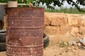 A rusty old oil can stands in arid, hot land next to old car tires on dry earth Royalty Free Stock Photo