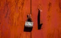 Rusty old padlock on red metal door with cracked and scratch. Horizontal grunge texture Royalty Free Stock Photo