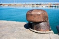 Rusty old steel mooring bollard with sea and fishing boats background Royalty Free Stock Photo