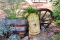 Rusty yellow farm jug used as a planter with a wagon wheel background Royalty Free Stock Photo