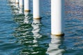 Rusty pier posts in salt sea water. White columns diagonal. Pillars mount for bridge. Sunny weather Royalty Free Stock Photo