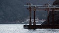 Rusty pier on rocky coast. Shot. Old ship`s wharf is empty on background of fishing house on rocky coast in cloudy Royalty Free Stock Photo