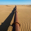 A rusty pipe goes into the distance through the desert. Royalty Free Stock Photo