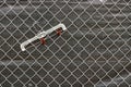 Rusty plastic garment hanger hanging on chain link fence with a gray tarp behind the fence Royalty Free Stock Photo