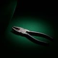 Rusty pliers are illuminated under focused, moody lighting on a textured green surface Royalty Free Stock Photo