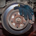 Rusty rear hub of a car wheel with a brake disc and a working black glove. A car without a wheel