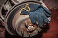 Rusty rear hub of a car wheel with a brake disc and a working black glove. A car without a wheel