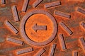 rusty red brown color textured cast iron manhole cover closeup detail. arrow, circle and spiral pattern Royalty Free Stock Photo