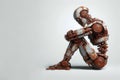 A rusty robot sits on the floor in thought. Space for text.