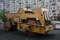 Rusty roller for laying asphalt. Town, street, multi-storey buil