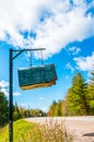 Weathered rural mailbox hanging from chains & metal post at road Royalty Free Stock Photo
