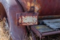 An rusty Saskatchewan license plate attached to an abandoned classic car