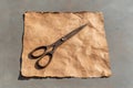 Rusty scissors on crumpled brown paper