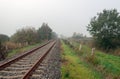 Rusty seemingly endless single track train tracks through a rural Dutch area with early morning fog Royalty Free Stock Photo