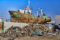 Rusty ship stands behind a pile of rubbish for repair work in the port dry dock Royalty Free Stock Photo