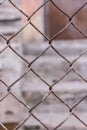 Rusty steel chain link or wire mesh as boundary wall. There is still concrete block wall behind the mesh.