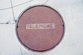 Rusty telephone manhole cover in cracked pavement Royalty Free Stock Photo