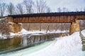 A rusty train tressel over water in winter.