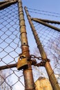 Rusty vintage metallic padlock hangs on wire netting gate