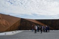 Rusty wall of memory with image of Russian soldiers who died in world war. Elderly tourists on excursion take photos