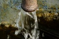 rusty water spout in bright light with blurred background and soft water flow in motion blur