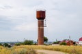 Rusty water tower against sky. Old water pump